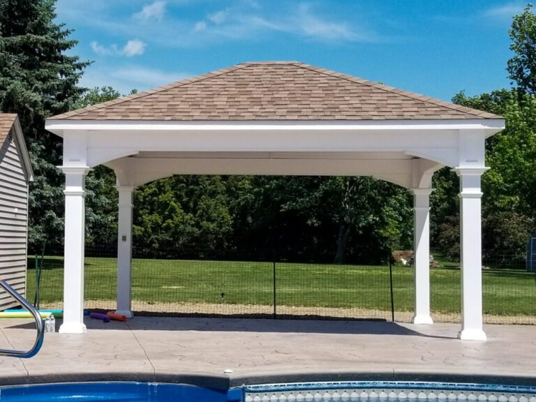 White vinyl pavilion with a shingled hip roof and open sides on a stamped concrete pool deck