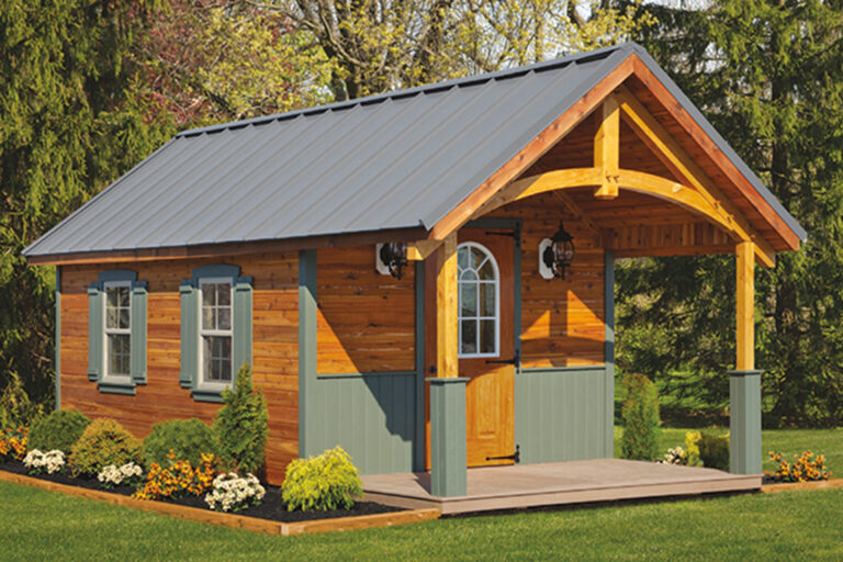 Cedar-sided shed with a metal roof, green trim and a covered porch with timber trusses